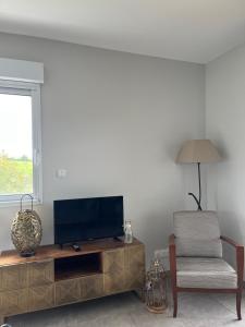 a living room with a flat screen tv and a chair at Gites de Landuzière in Étrat