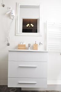 La salle de bains blanche est pourvue d'un lavabo et d'un miroir. dans l'établissement Antique Hostel, à Bucarest