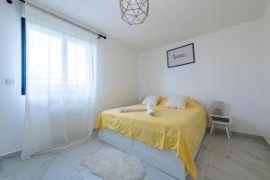 Un dormitorio blanco con una cama con una manta amarilla. en Le Cosy proche Disney, en Vaires-sur-Marne 1 foto más