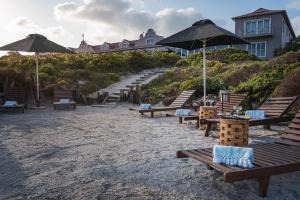 a group of benches and umbrellas on a beach at Blue Bay Lodge in Saldanha