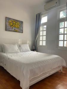 a bedroom with a large white bed with two windows at Dứa Homestay Mũi Né in Ấp Thiện Phước