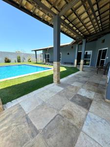 un patio extérieur avec une piscine et une pergola dans l'établissement Casa Brisa do mar, à Paracuru
