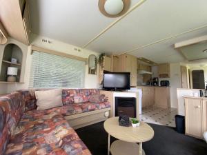 a living room with a couch and a tv at Gastenverblijf op rustige camping in Zeeland in Kats