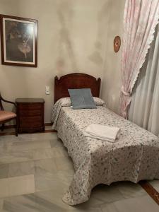 a small bedroom with a bed and a chair at Los Magnolios SXXI in Lucena +6 photos