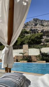 a bed with a canopy next to a swimming pool at Theonia Villas in Pefki Rhodes