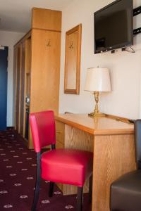 レザンにあるアルパイン クラシック ホテルのデスクと赤い椅子が備わる客室です。