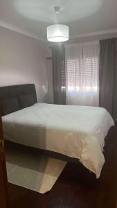 Un dormitorio con una cama blanca y una ventana. en Grand logement 3 pièces, en Venda Seca