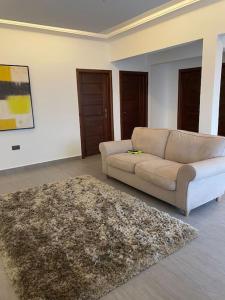 a living room with a couch and a rug at Cozy 2 BR apartment in Ajiringano