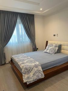 a bedroom with a bed and a window with curtains at Cozy 2 BR apartment in Ajiringano