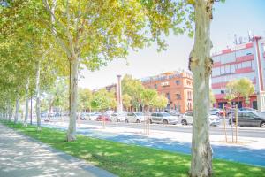 a tree lined street with cars parked in a parking lot at Torneo 48 Suite in Seville