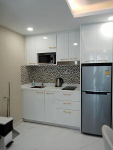 a kitchen with white cabinets and a stainless steel refrigerator at Dusit grand park 2 in Jomtien Beach
