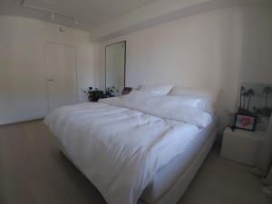 a large white bed in a white bedroom at Stilren leilighet midt på Lade in Trondheim