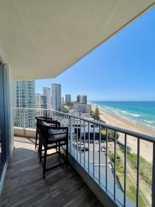 a balcony with a table and chairs and the beach at Absolute Beachfront Luxury - Heated Pool - 75 TV in Gold Coast