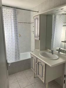 a bathroom with a sink and a tub and a mirror at La Magie entre deux lacs in Gérardmer
