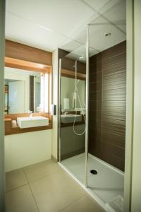 uma casa de banho com uma cabina de duche em vidro e um lavatório. em Campanile Dijon Congrès Clemenceau em Dijon