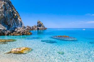 a beach with rocks in the ocean with blue water at LA TORRE SARACENA - APARTMENTS with services & Free Parking in Palmi