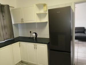 a kitchen with a black refrigerator and white cabinets at Corona Del Mar 7 in Margate
