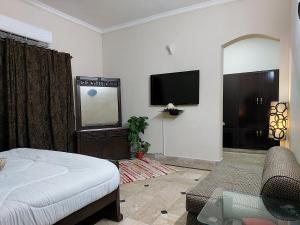 a living room with a bed and a tv at Green Residency, Eco-Friendly Guestrooms available for Families near Islamabad and Murree in Islamabad