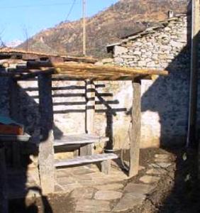 eine Holzbank auf der Seite eines Gebäudes in der Unterkunft Casa Elin in Maggia
