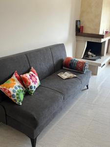 a gray couch with pillows in a living room with a fireplace at Casa Ivana in Castiglione del Lago