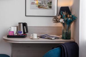 a table with a vase of flowers and a cup of coffee at Best Western Hôtel Royan Océan in Royan