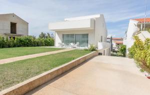 ein weißes Haus mit einem grasbewachsenen Hof in der Unterkunft Amazing Apartment In Marina Di Modica in Marina di Modica + 21 Fotos