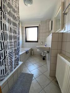 un bagno con vasca, lavandino e vasca da bagno di Am Quellberg Apartments Recklinghausen a Recklinghausen