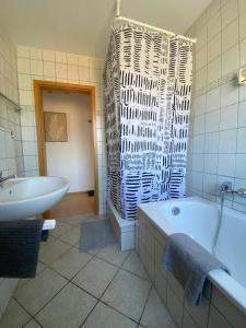 un bagno bianco con vasca e lavandino di Am Quellberg Apartments Recklinghausen a Recklinghausen Altre 6 foto