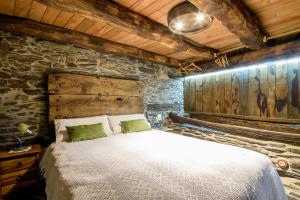 a bedroom with a bed and a stone wall at As Casias d'Oscos in Villanueva de Oscos