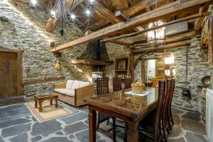 a dining room with a wooden table and a couch at As Casias d'Oscos in Villanueva de Oscos