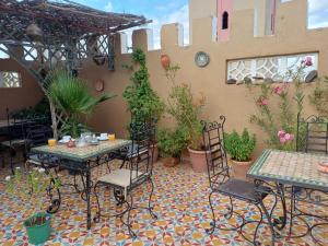 an outdoor patio with tables and chairs and potted plants at Chambres d'Hôtes les amis in Taroudant