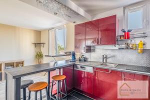 a kitchen with red cabinets and two bar stools at Jolie T3 50m² (+-), balcon, parking, commodités in Vénissieux