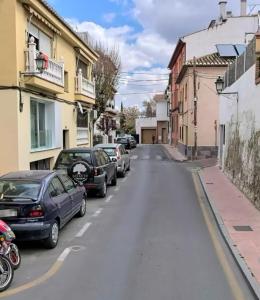 una calle vacía con coches aparcados en una ciudad en Ruralya Herreria home, en La Zubia