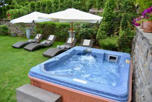 a hot tub in a yard with chairs and an umbrella at Villa Vuchev in Velingrad