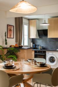a kitchen with a wooden table and a dining room at Orphée by Kleidos - Disney 10min! Superbe T2, 4P, Parking gratuit, Balcon in Magny-le-Hongre