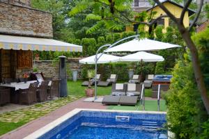 a pool with chairs and umbrellas next to a house at Villa Vuchev in Velingrad