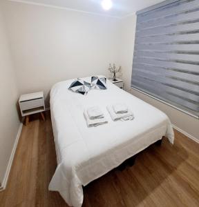 a bedroom with a large white bed with a window at Comodo Dpto. 4to piso - 2P/2B Excelente Conectividad/Buen Sector - Brisas Del Sol in Talcahuano