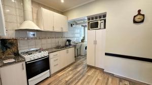 a kitchen with white cabinets and a stove top oven at Casa Miriam - Casa En Miramar Para 4 PAX Con Cochera - Hola Sur in Miramar