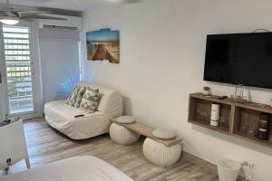 uma sala de estar com um sofá e uma televisão de ecrã plano em Relaxing Studio Near El Yunque With Pool View em Luquillo