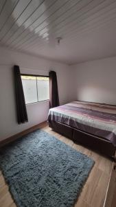 a bedroom with a bed and a rug and a window at Casa família Mota in Brotas