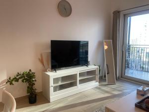 una sala de estar con TV de pantalla plana en un armario blanco en F1 - Daisy Hill 1BR Waters Edge Canal View Yas island - Theme Parks, en Abu Dabi