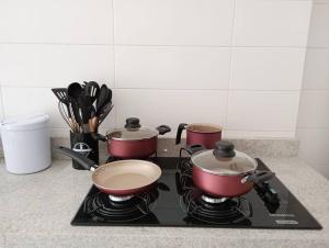 a stove top with three pots and pans on it at Apartamento Normandie, Itapajé in Frederico Westphalen