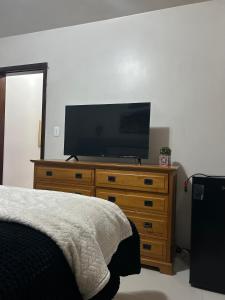 a bedroom with a flat screen tv on a dresser at Casa bucólica para casais apaixonados in Flores da Cunha