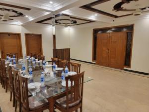 a conference room with a long glass table and chairs at Airport Guest House - JIA in Karachi