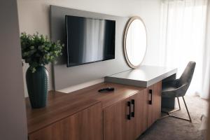 a television on top of a wooden dresser with a mirror at Pensiunea Berzasca in Berzasca