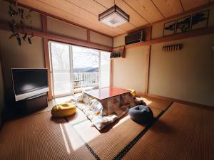 a living room with a table and a large window at Sakazuki Forest Bump in Higashiizu