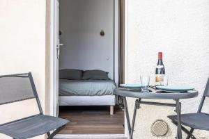 a room with a table with a bottle of wine and a bed at Studio Cosy Terrasse au Calme CDG Disney in Chelles
