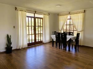 a dining room with a table and chairs and windows at Casa de campo in Oxapampa