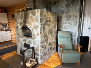 a stone fireplace with a chair in a room at Villa Ossa in Tervola