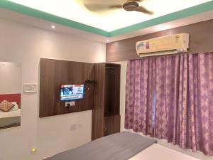 a room with a bed and a tv in a room at Phoenix Lodge in Siliguri